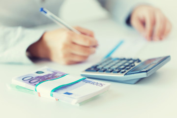 close up of hands counting money with calculator