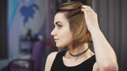 Fototapeta premium Beautiful brown-haired woman in a beauty salon appreciates his new hairstyle.