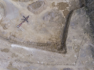 Aerial view of excavator and truck working on the field of sand