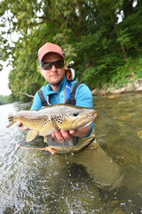 Fly fisherman holding brown trout out of water