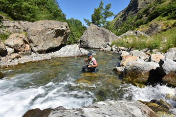 Fisherman trout fishing with bait in mountain river