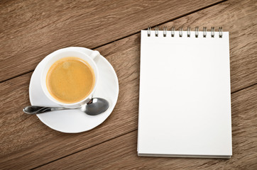 Cup of coffee in a white cup and spiral notepad