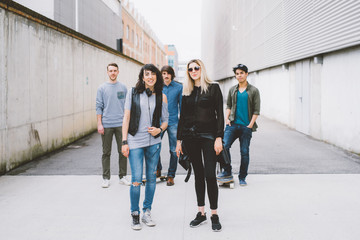 Obraz premium Group of young multiethnic woman and man friends posing in the street with their skateboard, looking in camera, smiling - friendship, sport concept