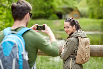 couple with backpacks taking picture by smartphone