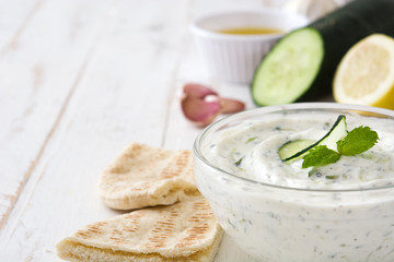 Tzatziki and ingredients on a white wooden table

