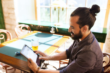 man with tablet pc drinking beer at bar or pub