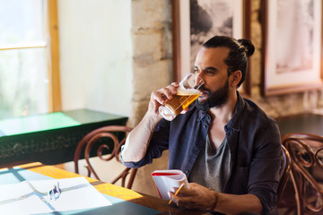man with notebook drinking beer at bar or pub