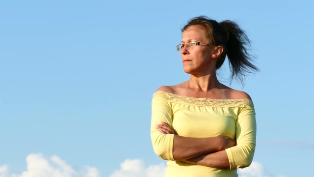 4K. Adult woman in yellow blouse   against blue sry