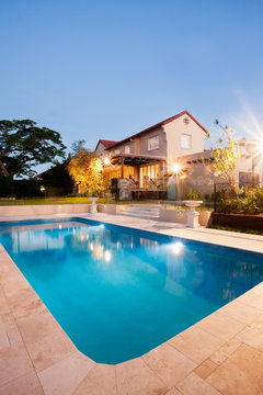 Modern swimming pool with mansion at night with lights