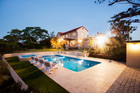 House and a garden with a pool illuminate with lights
