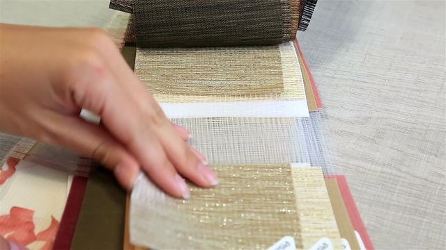 Female hand choses a textile sample for blinds
