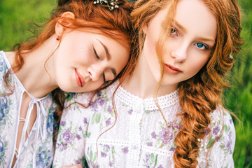 Portrait of two beautiful redhead girls in the spring garden