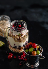 Muesli, fresh berries and yogurt in glass mason jar on wooden ta