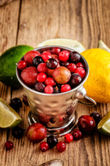 Small metal pail with different berries on wooden table