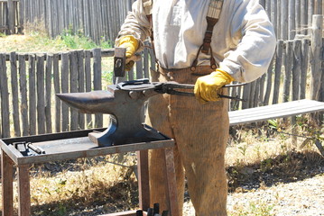 Male farrier working on a horseshoe outdoors.