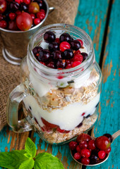 Muesli, fresh berries and yogurt in glass mason jar on wooden ta