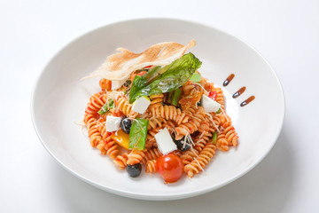 Pasta in tomato sauce with fried vegetables and fresh cherry tomatoes and feta
