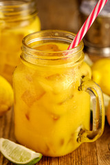 Fresh orange juice with ice in a mason jar on wooden table.