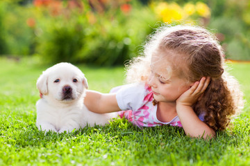 Little girl with a labrador puppy, outdoor summer