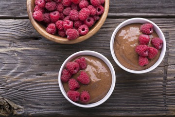 Chocolate Banana Smoothies served fresh juicy ripe raspberries with a sprig of mint in portioned bowls on  wooden background