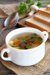 Easy mushroom soup with vegetables. Chopped bread on a kitchen cutting board, spoon, parsley, fresh champignons on a wooden table. Delicious mushroom soup recipe. Closeup