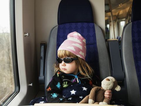 Girl wearing sunglasses and cap sitting in train