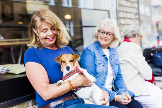 Senior woman holding dog at cafe