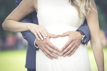 newlyweds - heart shaped men's hands on woman's belly