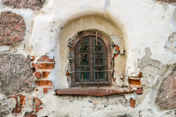 Fototapeta na wymiar A semicircular window with bars in an old brick building