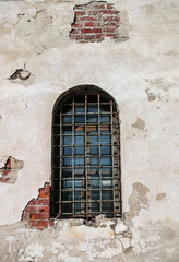 Fototapeta na wymiar A semicircular window with bars in an old brick building