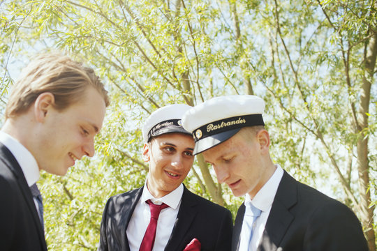 Male graduates talking at university park
