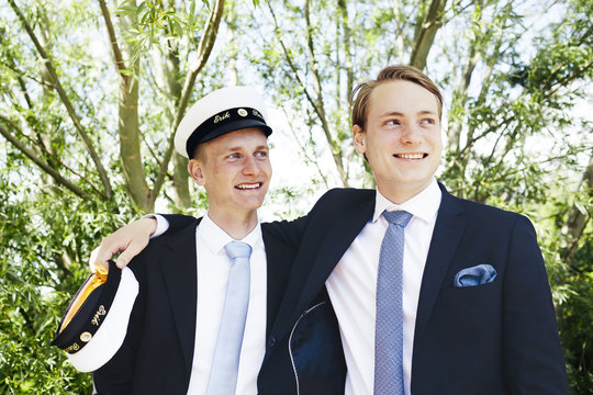 Happy male graduates looking away while standing at university park