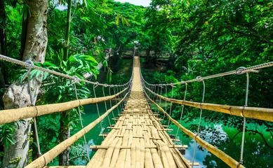 Foto op Plexiglas Bruggen Bamboe hangbrug over rivier in tropisch bos