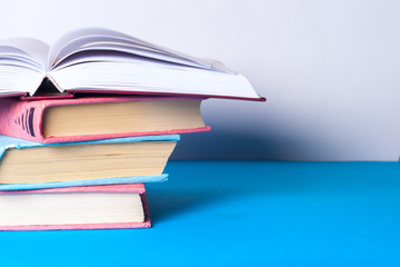 Open book, stack of colorful hardback books on light table. Back to school. Copy space for text