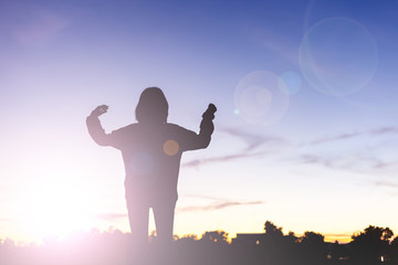 Silhouette of happy young woman over beautiful twilight sunset.