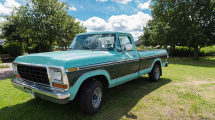 classical american truck standing on the grass before blue sky