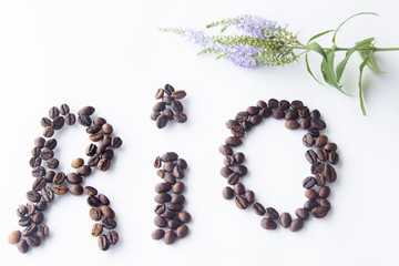 Coffee beans arranged shaped RIO heart on wood background.