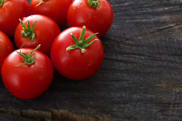 Red cherry tomatoes on black rustic wood background