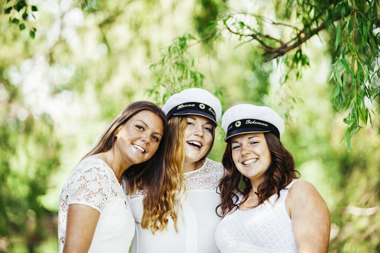 Portrait of cheerful female graduates at university park