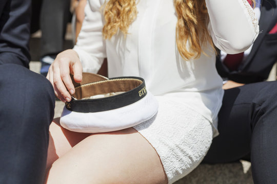Midsection of female student holding cap while sitting with male friends at graduation party