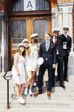 Happy male and female graduates standing on steps at graduation party
