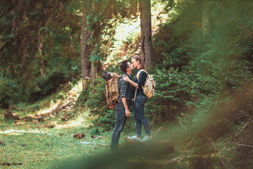 Couple of hikers Hiking with backpacks walk along a beautiful mountain area, are kissing. The concept of romance and active rest