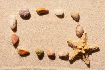Rectangular frame of sea stones and starfish on sand