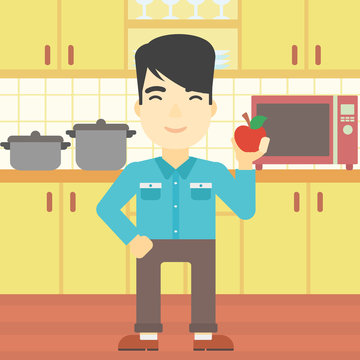 Young man with apple in the kitchen.