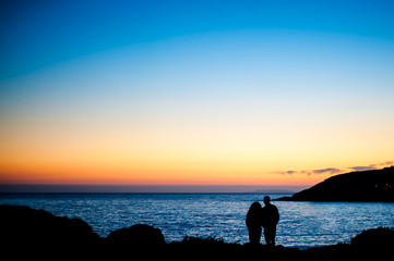 Silueta de una pareja frente al mar al anochecer