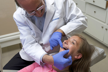 Model released image of young caucasian girl with braces being checked by the orthodontist