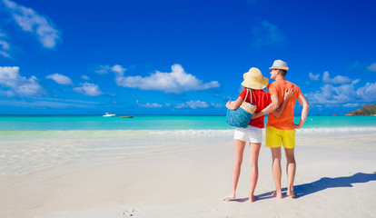 Couple in bright clothes on a tropical beach at Praslin, Seychelles.