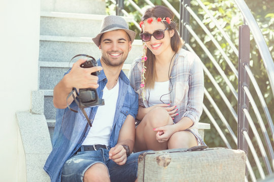 Happy young couple taking self portrait on their summer vacation. Young man is using old-fashioned camera to take a photo.