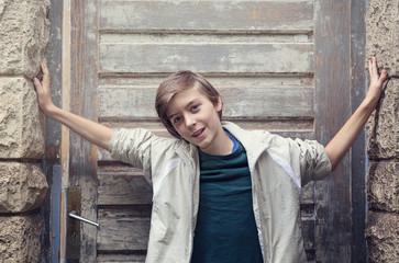 portrait of a smiling boy standing in front of an old entrance