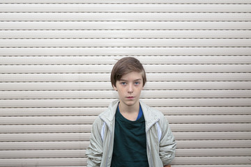 portrait of a boy with gray roller shutter in background